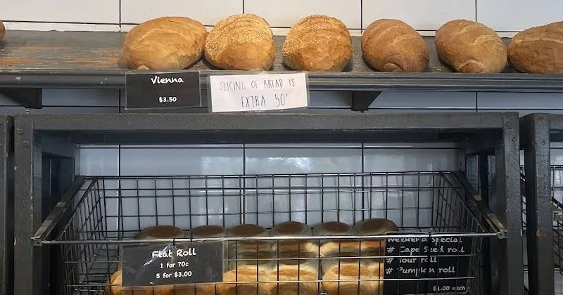 Loaves on the steel shelf with the black price tags: Vienna $3.50, Flat Roll 1 for 70c
