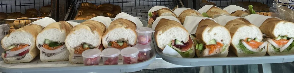 A tray of pork rolls wrapped in paper at the front of the counter, with little tubs of chilli
